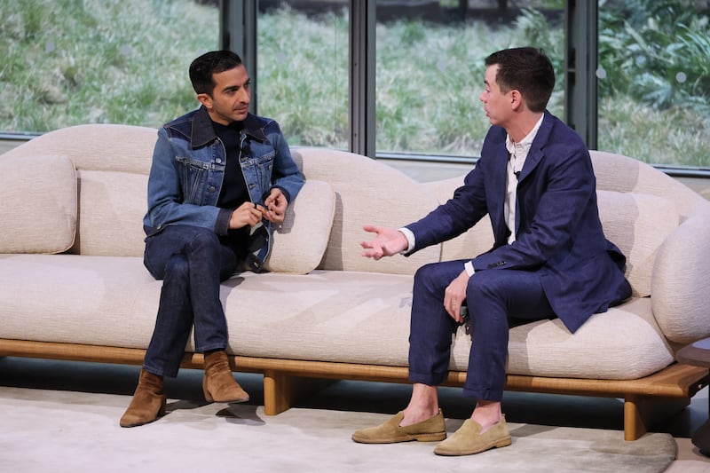 Two men chat on a couch on stage at a tech conference